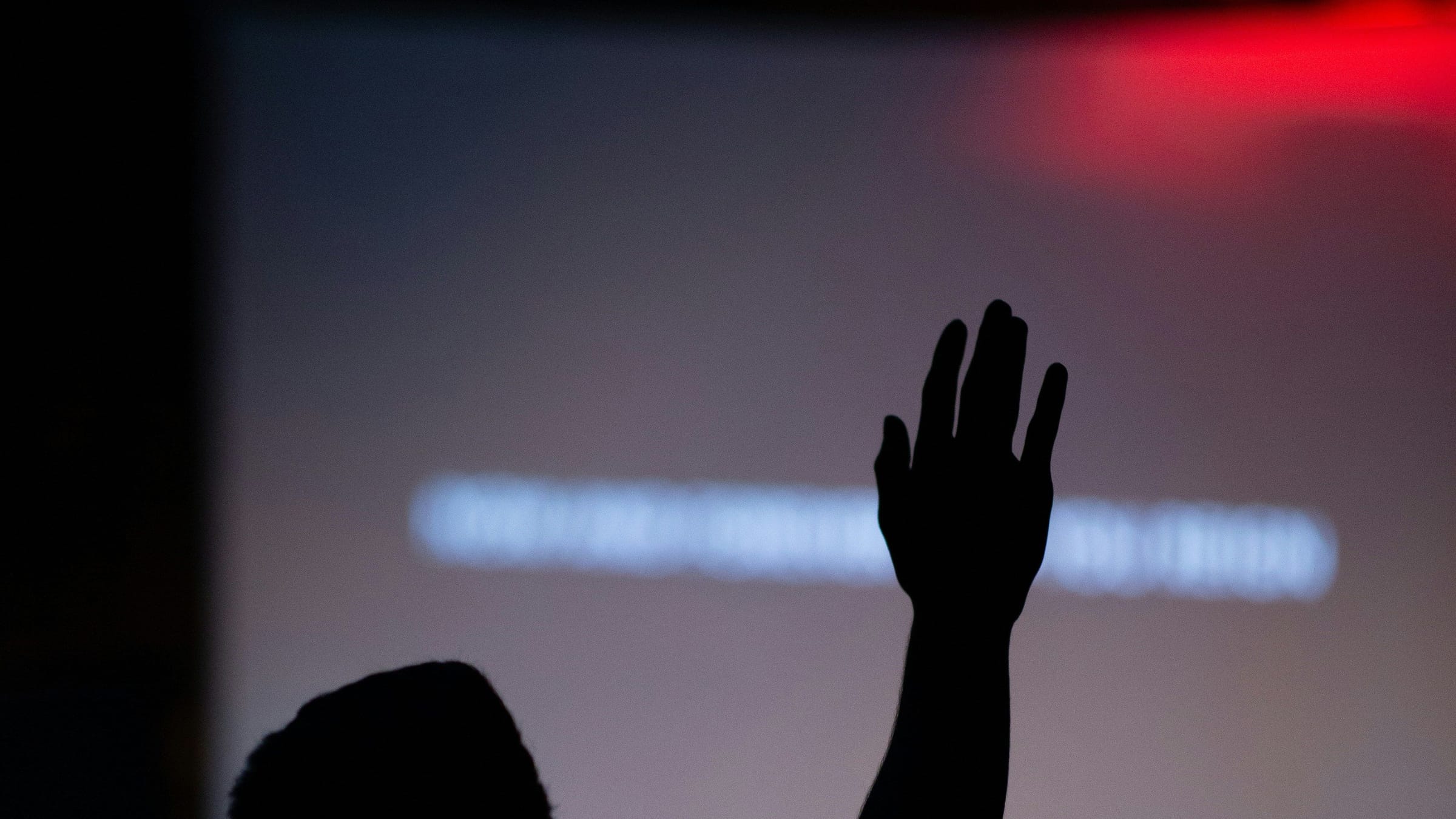 Silueta de una persona con la mano levantada durante la adoración