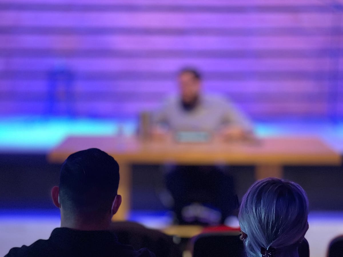 Auditorio de Comunidad Capital con el escenario iluminado en tonos morados durante una reunión de domingo